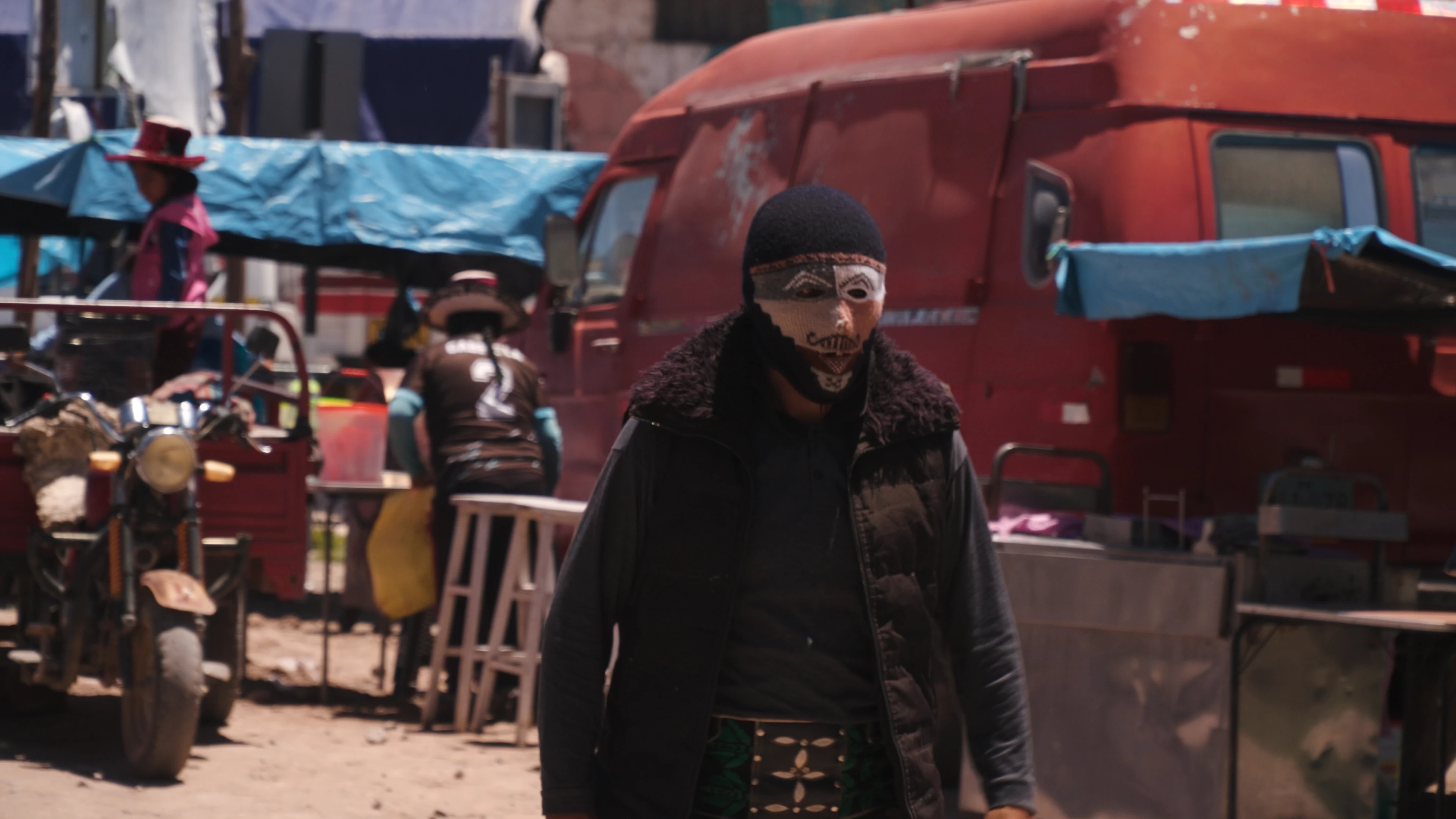 Masked figure walking through the Santo Tomás market on the morning of Takanakuy